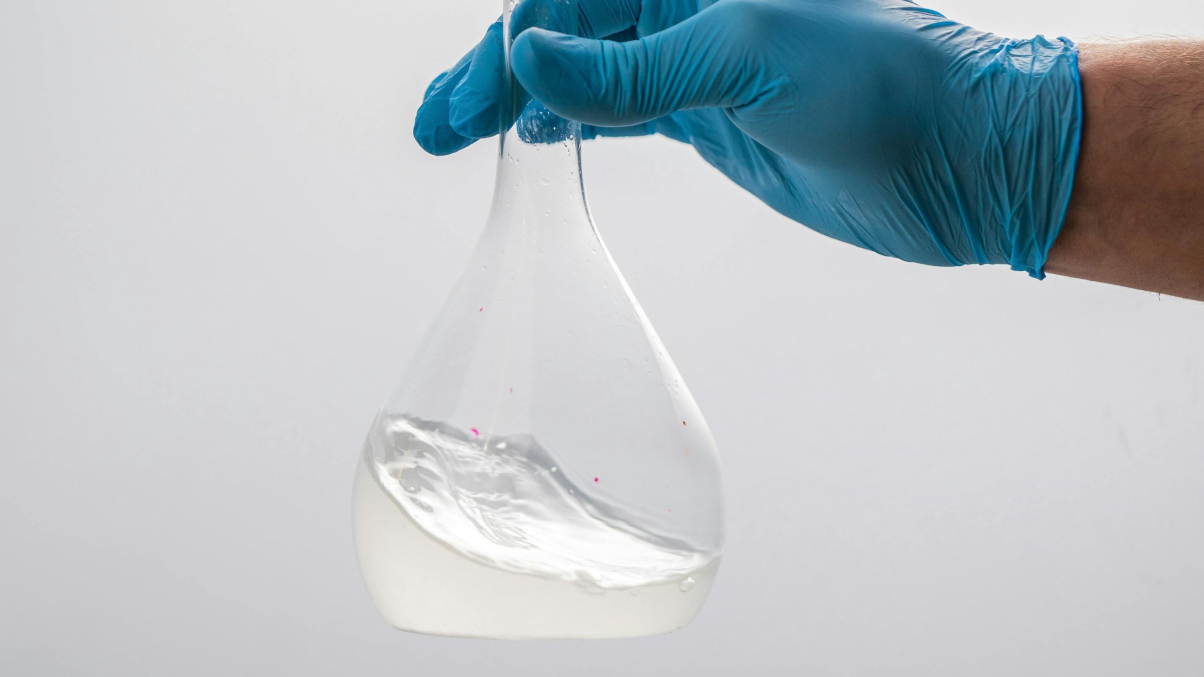 Research glass bottle with fluid and hand with blue gloves